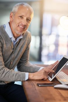 This tablet is the best tool for business. Portrait of a mature businessman using his digital tablet in the office.