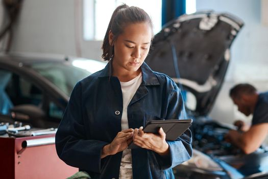The more diverse your knowledge, the more customers you can help. Shot of a female mechanic using a digital tablet while working in an auto repair shop.