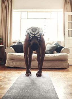 Bend down and feel the stretch. Shot of a sporty young man touching his feet while exercising at home.
