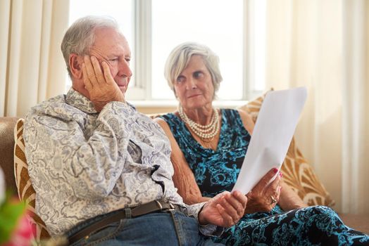 Less income, challenging outcomes. Shot of a senior couple going through their paperwork together at home and looking worried.