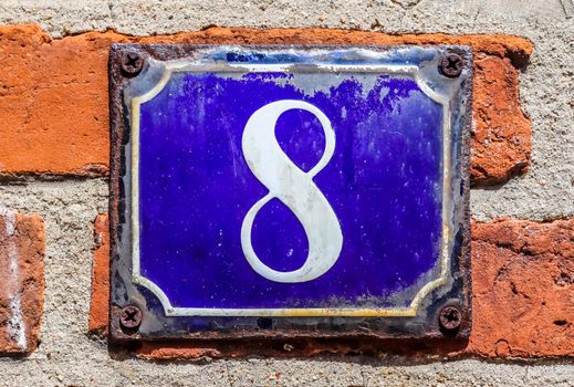 Old brick wall. Texture of old weathered brick wall with a number 8 on a blue sign