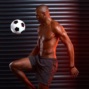 Perfect first touch. Studio shot of an athletic young man playing with a soccer ball against a grey background.