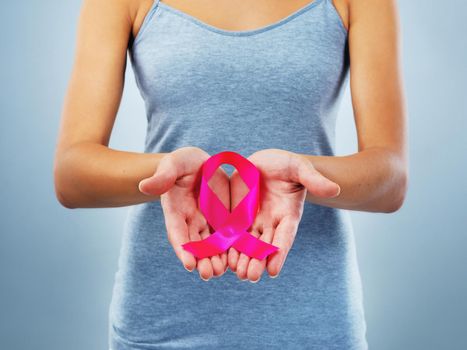 Create awareness not only for yourself but for others. Studio shot of an unrecognizable woman holding a breast cancer awareness ribbon against a blue background.