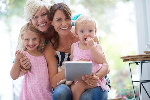 The perfect modern family. Portrait of a lesbian couple showing their daughters how to use a digital tablet.