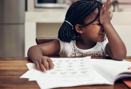 This needs some careful thinking. Cropped shot of an adorable little girl thinking hard while doing her homework at home.