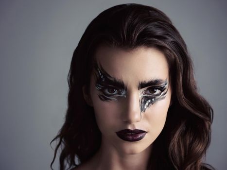 Come over to the dark side. Studio shot of an attractive young woman wearing bold makeup.