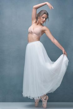 Shot of a beautiful young woman posing in studio while wearing a bra and ballet skirt.