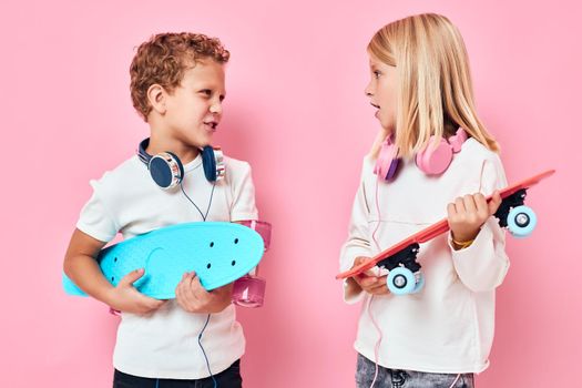 Stylish little boy and cute girl skateboards in the hands of entertainment isolated background