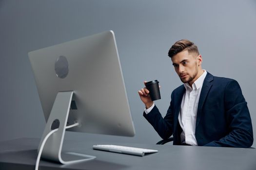 a man in a suit sitting at a desk in front of a computer isolated background