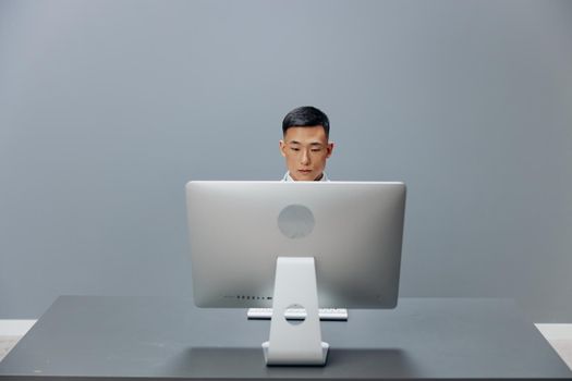 man working in front of computer sitting at a table in the office isolated background