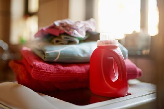 Keeping your laundry clean. Shot of a bottle of detergent and a pile of laundry on top of a washing machine.