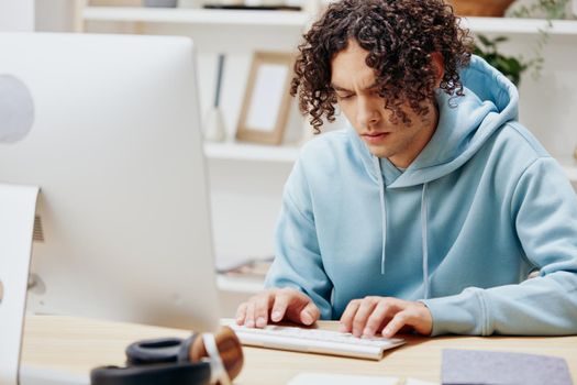 guy with curly hair in a blue jacket in front of a computer Lifestyle. High quality photo