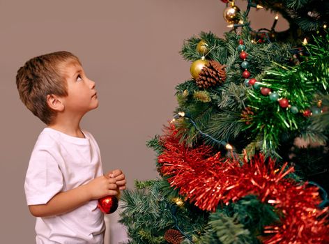 Christmas is a time of child-like wonder.... A young boy decorating a Christmas tree.