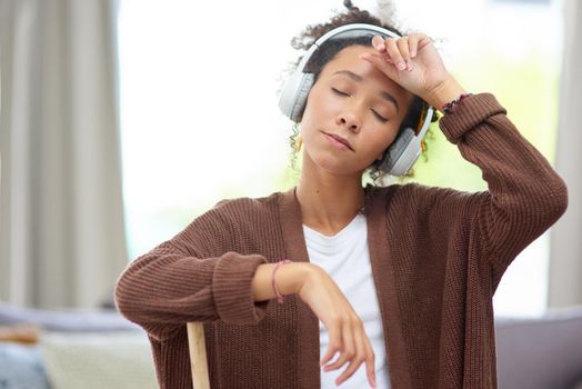 Do you have any idea how exhausting cleaning can be. Shot of a woman wearing headphones and looking exhausted after cleaning her house.