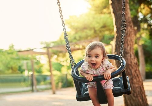 I love this swing. Shot of little girl playing on a swing in a park.