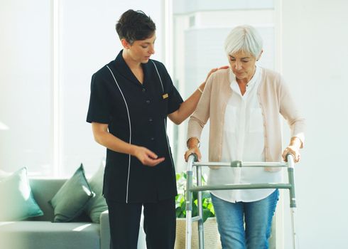 Cropped shot of an attractive young healthcare professional helping her senior patient walk with a walker in a nursing home.