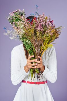 Id rather pick flowers instead of fights. Studio shot of a woman standing with a bunch of flowers in front of her face.