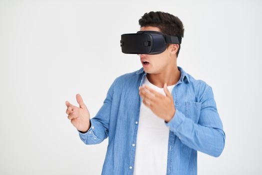 Escape into cyberspace. Studio shot of a young man looking amazed while wearing a VR headset against a white background.