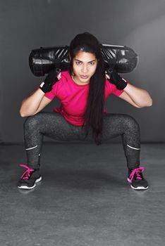 What a lot I squat. Studio shot of an attractive young woman working out with dumbbells against a gray background.