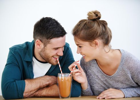 Stop sipping so fast. Shot of an attractive young couple sharing a milkshake together.