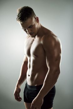 Hes a muscle making machine. Studio shot of a muscular young man posing against a grey background.