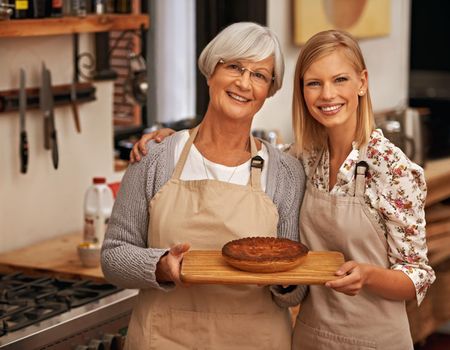 Bonding over baking. Shot of a young woman and her grandmother showing off their baking skills.