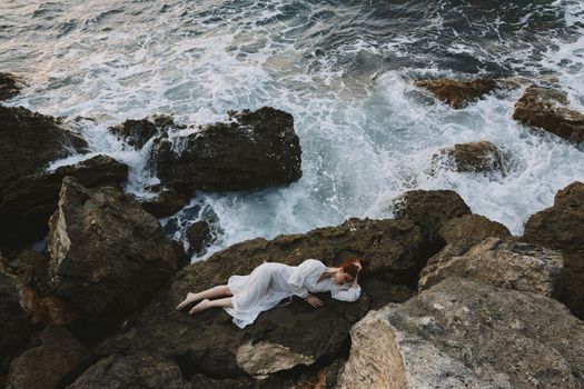 Barefoot woman lying on rocky coast with cracks on rocky surface vacation concept