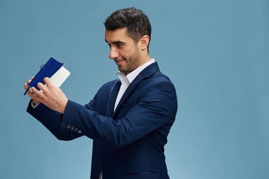 businessmen with an open notebook in his hands looking for something business and office concept blue studio background, copy space