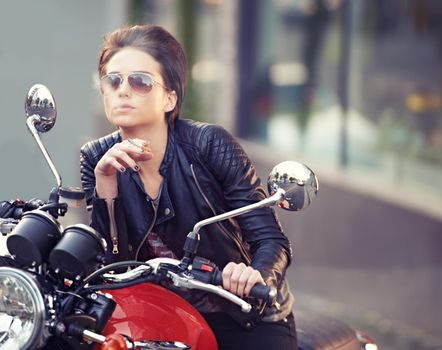 Shes an easy rider.... Shot of a young female biker smoking a cigarette.