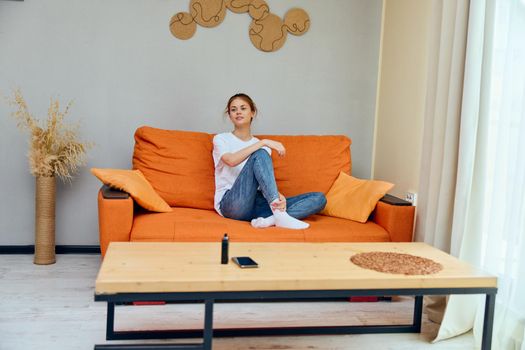 woman at home on orange sofa phone on table and vape