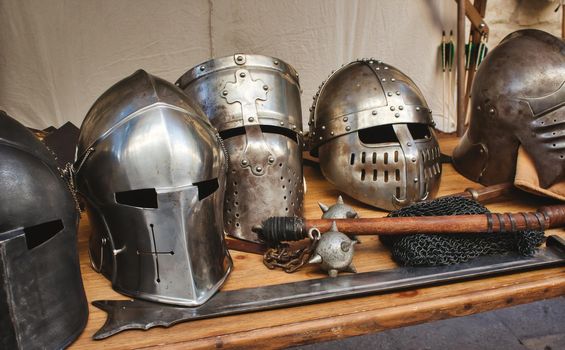 Shiny metal helmets of medieval knights with traditional weapons at a middle age theme festival