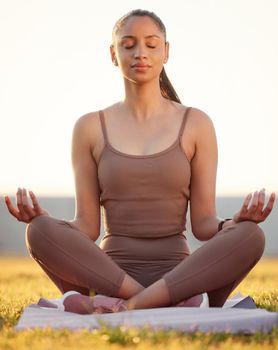 Enjoying her time in a garden of zen. Shot of a sporty young woman meditating while exercising outdoors.