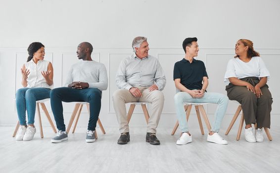 We can learn a lot by listening to each others stories. Shot of a diverse group of people talking to each other while sitting in line against a white background.