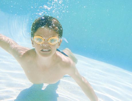Hes a very good swimmer. Shot of a little boy wearing swimming goggles while swimming underwater.