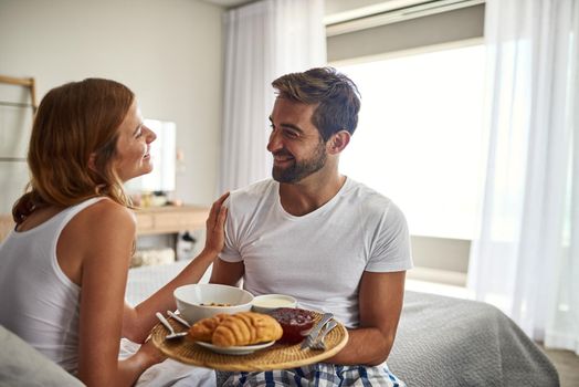 Romance is, breakfast in bed. Shot of a happy young couple enjoying breakfast in bed together at home.