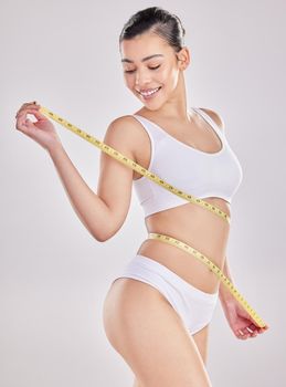If youre feeling good on the inside, youre looking great on the outside. Studio shot of a fit young woman holding a measuring tape around her waist.