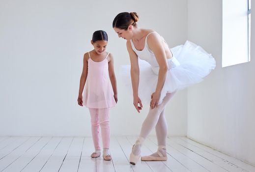 Position your feet like this. Shot of a little girl practicing ballet with her teacher in a dance studio.