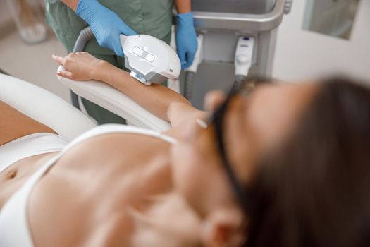 Closeup of hair removal procedure on arms with ipl machine from a professional cosmetologist