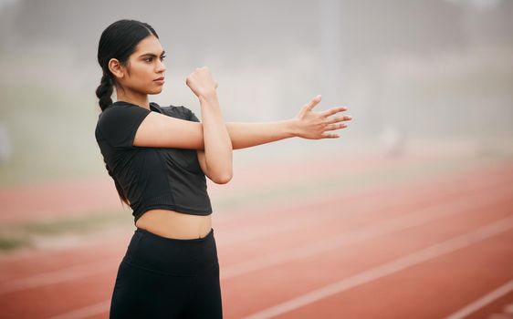 If youre confident, youll achieve anything you put your mind to. Shot of an athletic young woman stretching while out on the track.