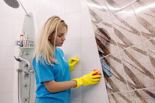 Belarus Minsk 06 29 2018 :Blonde woman, employee cleaning company, wearing in yellow protective rubber gloves, with special cleaning sponge, Housework and housekeeping concept.