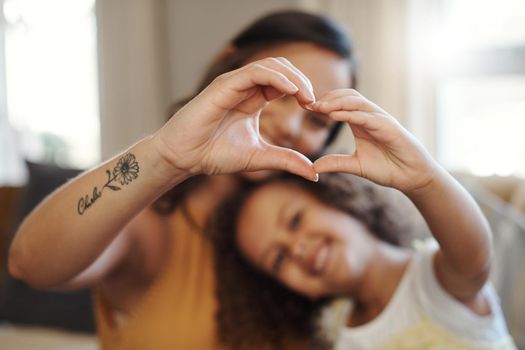 Weve got lots of love to share. Shot of an unrecognizable woman bonding with her daughter at home and making a heart-shaped gesture.
