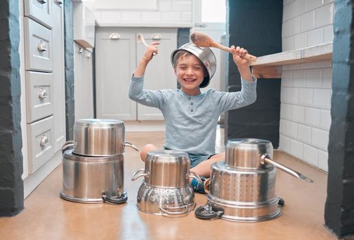 Share your smile with the world. Shot of an adorable little boy playing with pots in the kitchen.