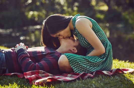 Shot of an affectionate young couple relaxing together on a picnic blanket in the park.