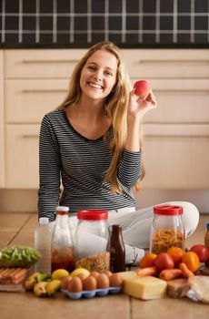 Shot of an attractive young woman surrounded by various food in the kitchen at home.