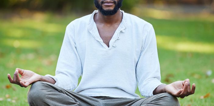On the search for inner peace. Cropped shot of an unrecognizable young man meditating while practicing yoga outside at the park.