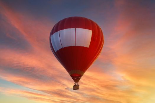Red hot air balloon flying in the sky at sunset or sunrise