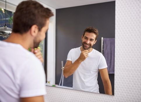 I do look good with a beard though. Cropped shot of a handsome man looking at himself in the mirror whilst touching his beard at home.