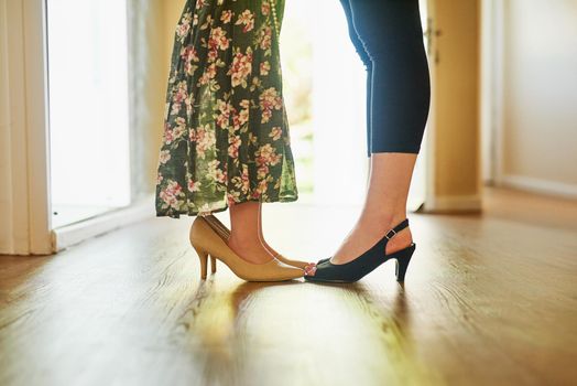 Cropped shot of a mother and her little daughter wearing high heels at home.
