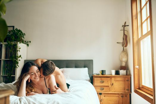 Lets stay in and cuddle. Shot of an affectionate young couple spending a romantic morning in bed at home.