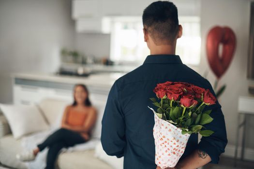 Ive got a surprise for you. Shot of a young man surprising his wife with flowers at home.